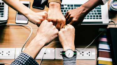 Bild fist bump über Tisch mit Laptops